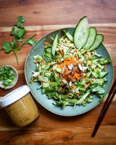 a green plate topped with salad next to a jar of mustard and chopsticks