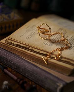 an open book with two gold rings on it and a chain hanging from the pages