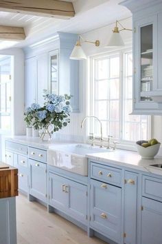 a kitchen with blue cabinets and white counter tops is pictured in this image, there are two vases on the sink