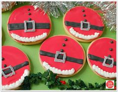 decorated cookies with santa's belt and buckles are on a green tablecloth