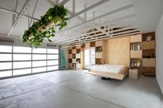 an empty room with a bed and plant hanging from the ceiling in front of it