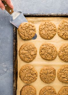 someone is spreading icing on top of cookies in a baking pan with parchment paper