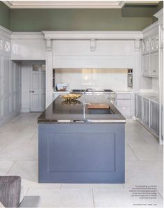 a large kitchen with an island in the middle and white cabinets on both sides is featured in this magazine