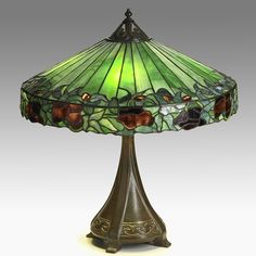 a lamp that is sitting on top of a table with a green shade over it