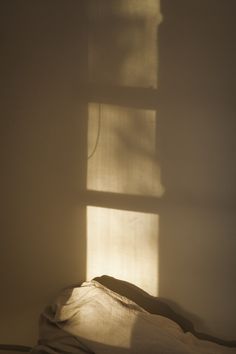 the shadow of a window on a bed in a room with white walls and sheets