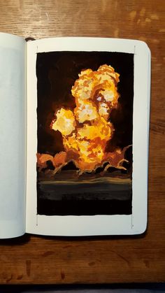 an open book on a wooden table with a painting in the middle and yellow flames coming out of it