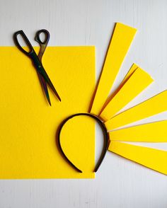 scissors and yellow paper laid out on top of each other next to a pair of scissors