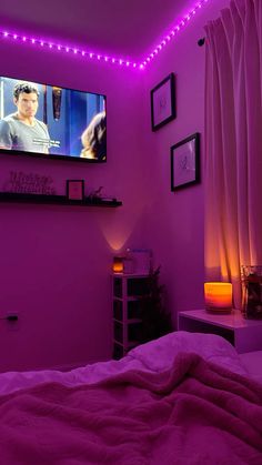 a bedroom with purple lights and a flat screen tv mounted above the bed, along with pictures on the wall