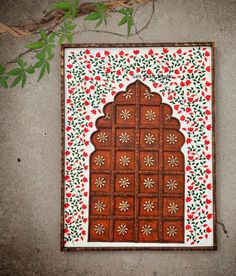 an intricately decorated wooden panel with red and green flowers on the outside, in front of a concrete wall