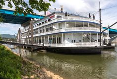 a large white and blue boat sitting on top of a river next to a bridge