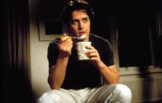 a man sitting on the floor eating and drinking from a cup