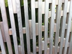 a close up of a wooden fence with plants in the background