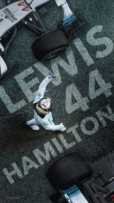 a man standing next to a racing car on top of a green carpeted floor