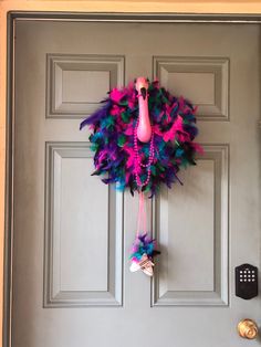 a door with a pink flamingo wreath hanging on it's side and a remote control attached to the front door