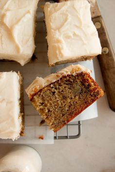 slices of carrot cake with white frosting on a cutting board next to a knife