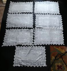 four pieces of white lace laid out on a black tablecloth with the edges cut off