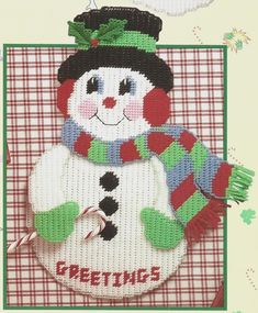 a snowman with a green hat and scarf on it's head, standing in front of a red checkered background