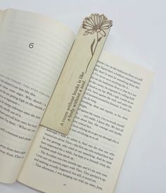 an open book with a wooden bookmark attached to it's cover, sitting on a table