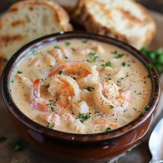 a bowl of soup with shrimp and bread on the side, ready to be eaten