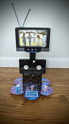 an old tv sitting on top of two dvd's in front of a wooden floor