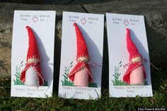 three small red and white gnomes are on the grass next to each other,