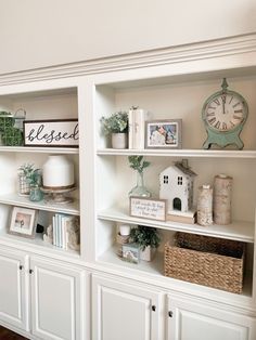 a white bookcase filled with lots of books next to a clock and other items