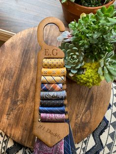 a wooden rack with many different types of ties on it next to a potted plant