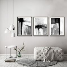 three black and white paintings hanging on the wall in a living room with a couch