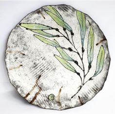 a white plate with green leaves painted on it