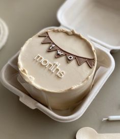 a cake in a container with the words months on it and spoons next to it