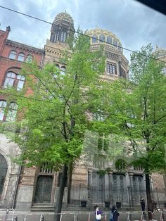 people walking on the sidewalk in front of an old building