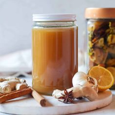 two jars filled with different types of food and spices on top of a white table