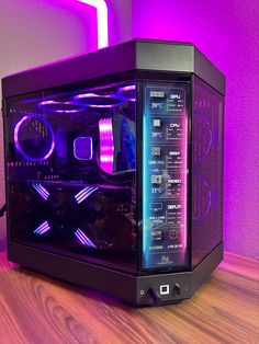 a black computer case sitting on top of a wooden table next to a purple light