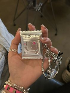 a person holding up a hello kitty phone case in their left hand and some bracelets on the other