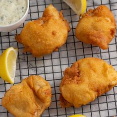 some fried food on a cooling rack with lemon wedges