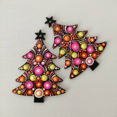 two christmas trees made out of paper with black stars on top and pink, yellow, orange, and green designs