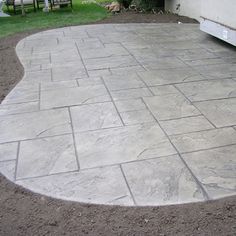 an outdoor patio area with stone pavers and bench in the background, surrounded by green grass