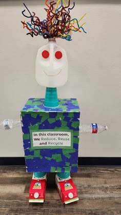 a cardboard box that has a face on top of it and some colorful streamers coming out of its head