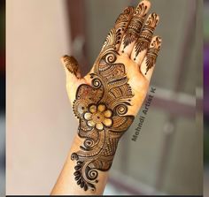 a woman's hand with henna tattoos on it, showing the intricate design