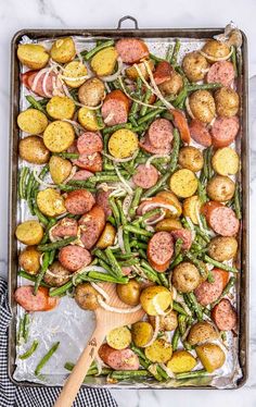 a sheet pan filled with potatoes, green beans and sausage