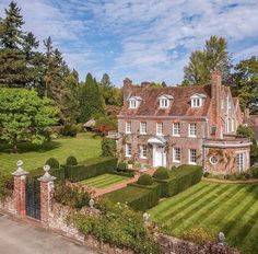 an aerial view of a large brick house with hedges and trees in the front yard