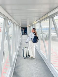 a woman is walking with her luggage down the walkway