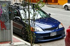 a blue car parked next to a parking meter with graffiti on the side of it