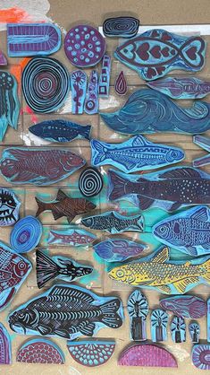 a bunch of fish that are sitting on a piece of cardboard with some colored paint