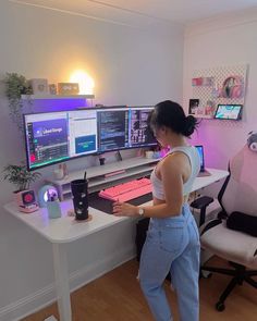 a woman standing at a desk with two computer monitors and a keyboard in front of her