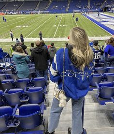 a woman is standing in the stands at a football game with her back to the camera