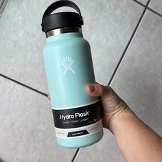 a hand holding a hydro flask water bottle in front of a tile floor with the words hydro flask on it