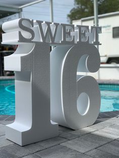 there is a sign that says sweet sixteen in front of a swimming pool