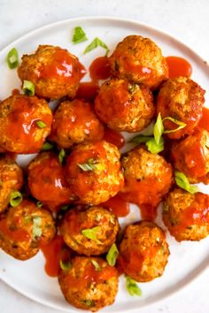 meatballs covered in marinara sauce and garnished with parsley on a white plate