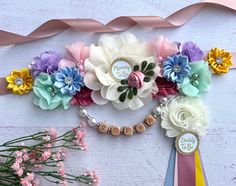 a bunch of flowers that are next to some ribbon and beads on a table with ribbons